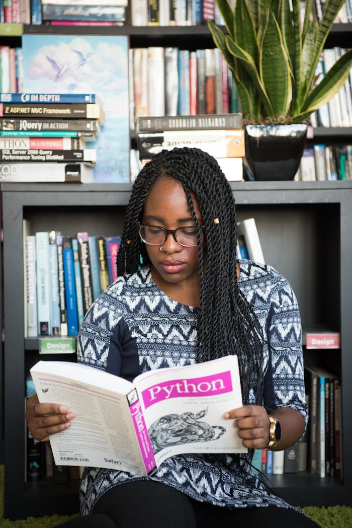 African American woman studying Python programming in a library setting.